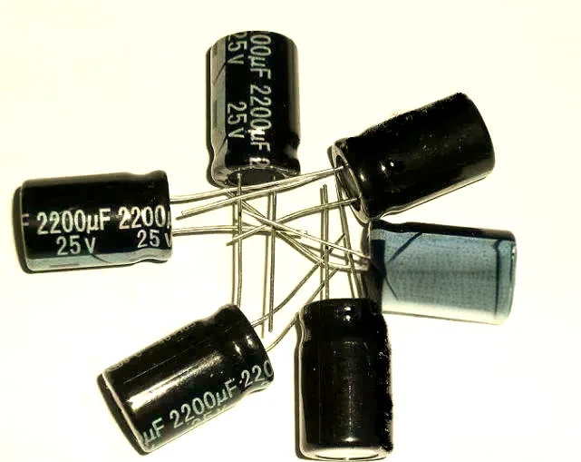 Close-up shot of six black aluminum electrolytic capacitors arranged in a star pattern showing the capacitance and voltage markings.