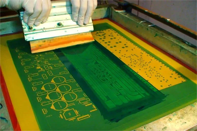Operator performing PCB silkscreen printing using a squeegee
