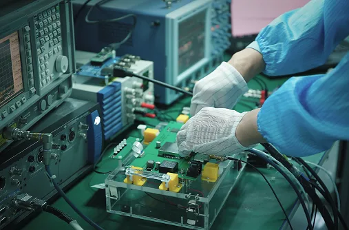 Engineer in cleanroom attire performing DFM and DFT validation on a medical PCBA using test equipment.