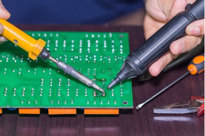 A professional soldering iron with a clean, tinned tip being used to melt solder on a PCBA