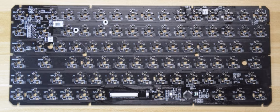 Black mechanical keyboard circuit board with numerous switch footprints and solder joints, no keys installed.